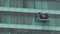 Pekerja terlihat tengah membersihkan kaca gedung di Bundaran HI, Jakarta, dengan menggunakan gondola, Senin (8/9/14). (Liputan6.com/Johan Tallo)
