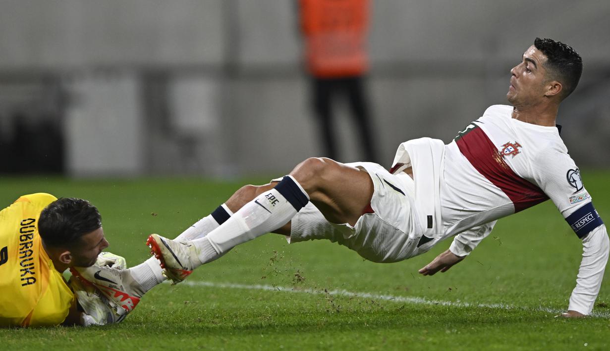 Penyerang Portugal Cristiano Ronaldo melakukan pelanggaran terhadap kiper Slovakia Martin Dubravka dalam laga Grup J Kualifikasi Euro 2024 di Stadion Tehelne pole, Bratislava, Sabtu (9/9/2023) dini hari WIB. (AP Photo/Radovan Stoklasa)