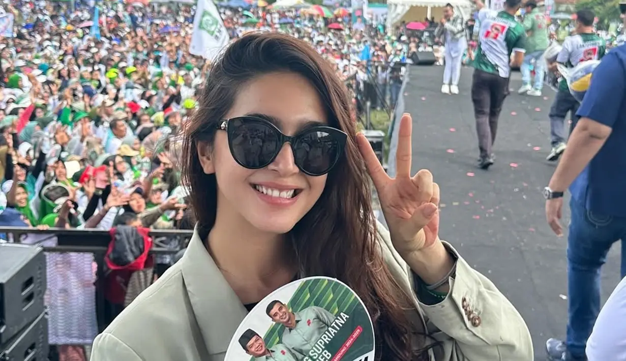 Tampil pakai blazer warna hijau, Nabila Syakieb tampil stylish. Lantaran digelar di lapangan, artis berusia 39 tahun ini memakai kacamata hitam untuk menghindari silaunya cahaya matahari. Nomor urut Dadang Supriatna-Ali Syakieb adalah nomor dua, Nabila Syakieb berpose dua jari sembari memegang kipas tangan dengan gambar Dadang Supriatna dan Ali Syakieb. (Liputan6.com/IG/@nsyakieb85)