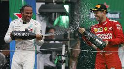 Pembalap Mercedes Lewis Hamilton, menyemprotkan sampanye ke arah pembalap Ferrari Sebastian Vettel setelah berhasil menjuarai balapan GP Meksiko di Autodromo Hermanos Rodriguez, Mexico City (28/10/2019). (AP Photo/Rebecca Blackwell)