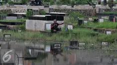 Seorang warga memancing ikan di Taman Pemakaman Umum (TPU) Tanah Kusir, Jakarta Selatan, Jumat (26/8). Warga memanfaatkan Banjir yang merendam makam di kawasan tanah kusir ini terjadi akibat luapan Sungai Pesanggrahan. (Liputan6.com/Johan Tallo)