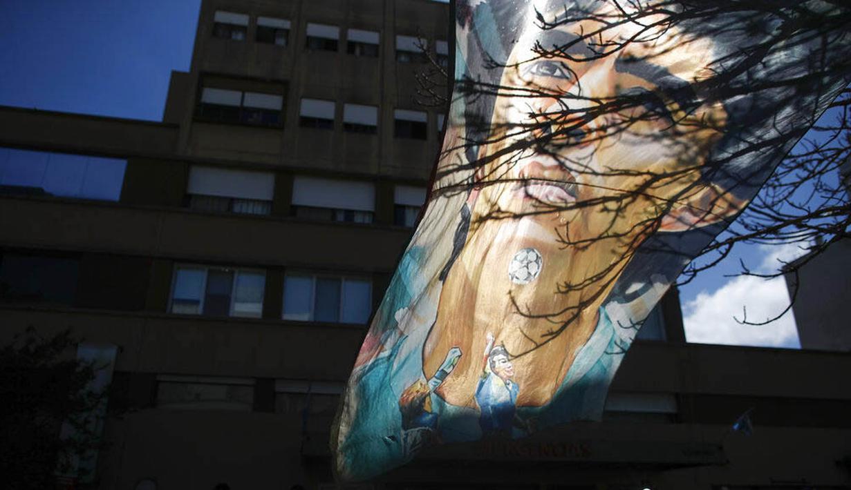 Bendera bergambar Diego Maradona berkibar di depan Rumah Sakit di La Plata, Argentina, Selasa (3/11/2020). Sejumlah fans Argentina berkumpul di depan rumah sakit untuk memberi dukungan kepada sang legenda. (AP/Natacha Pisarenko)