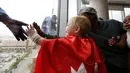Pasien anak berusaha menyentuh tangan superhero Superman yang membersihkan kaca jendela kamar di sebuah rumah sakit di Birmingham, Rabu (11/10). Para pekerja bergelantungan di luar jendela dengan mengenakan kostum superhero. (AP Photo/Brynn Anderson)