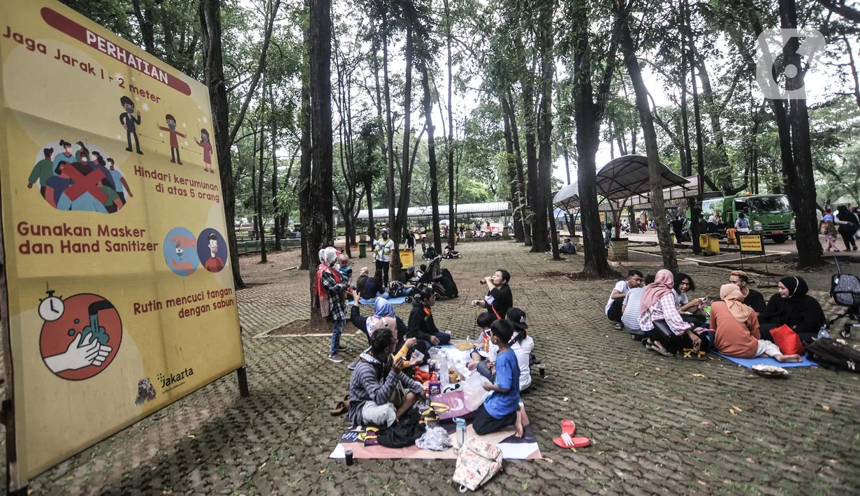 Wisatawan duduk di area dekat papan imbauan protokol kesehatan di Taman Margasatwa Ragunan, Jakarta, Jumat (14/5/2021). Taman Margasatwa Ragunan membatasi jumlah wisatawan dengan kapasitas 30 persen. (merdeka.com/Iqbal S. Nugroho)
