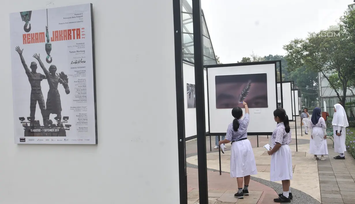 Siswa SD Negeri Menteng 01 mengamati karya foto yang dipamerkan dalam pameran fotografi Rekam Jakarta di Taman Menteng, Kamis (29/8/2019). Kegiatan tersebut dalam rangka edukasi bagi siswa mengenal profesi foto jurnalistik. (merdeka.com/Iqbal S Nugroho)