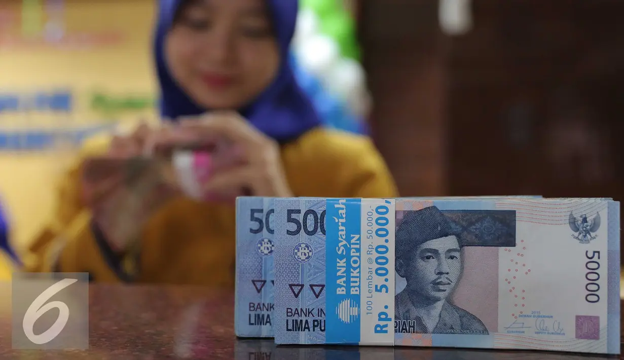 Teller menghitung uang rupiah di Bank Bukopin Syariah, Jakarta, Selasa (29/12). Rupiah kembali melemah, di tengah sepinya transaksi jelang libur Tahun Baru Hingga akhir pekan, pergerakan rupiah diperkirakan masih terbatas. (Liputan6.com/Angga Yuniar)