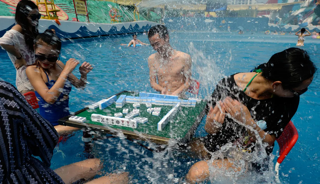 Pengunjung bermain mahjong di dalam kolam renang di wilayah Chongqing, Tiongkok, Rabu (2/8). Pemerintah setempat telah mengeluarkan peringatan merah terkait cuaca panas dengan suhu di beberapa daerah hampir mencapai 40 derajat celcius. (STR / AFP)