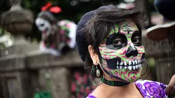 Seorang wanita berpakaian seperti "Catrina" ambil bagian dalam parade catrinas atau Hari Orang Mati di Reforma Avenue, Mexico City, 21 Oktober 2018. La Catrina diciptakan oleh artis Meksiko Jose Guadalupe Posada. (RODRIGO ARANGUA/AFP)