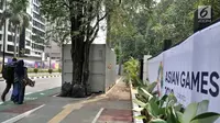 Pengendara sepeda melintas dekat kontainer tiket Asian Games 2018 yang berdiri di sepanjang trotoar Jalan Pintu 1 Senayan, Jakarta, Selasa (7/8). (Merdeka.com/Iqbal Nugroho)
