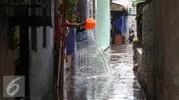 Seorang warga menguras air yang masuk kedalam rumahnya akibat banjir di kawasan Jatayu, Jakarta, Senin (21/11). Banjir disebabkan tingginya curah hujan dan buruknya saluran air serta meluapnya Kali Pesanggrahan. (Liputan6.com/Gempur M. Surya)