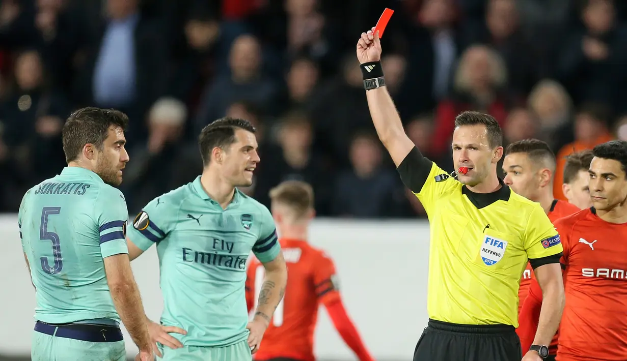 Wasit Ivan Kruzliak dari Slowakia memberikan kartu merah ke bek Arsenal, Sokratis Papastathopoulos selama pertandingan babak 16 besar Liga Europa di Roazhon Park Prancis (7/3). Rennes menang telak 3-1 atas Arsenal. (AP Photo/David Vincent)