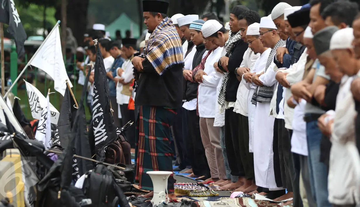 Massa aksi damai 4 November melaksanakan salat Jumat di Jalan Merdeka Barat, Jakarta, Jumat (4/11). Mereka menggelar salat Jumat di belakang pembatas beton dan mobil barakuda yang mengamankan kawasan itu. (Liputan6.com/Faizal Fanani)