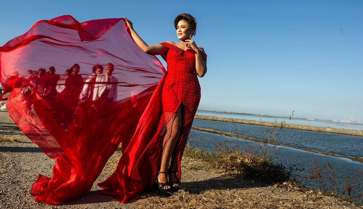 Model dengan balutan busana tradisional berlenggak-lenggok saat fashion show di tanggul Lapindo Porong, Sidoarjo, Jawa Timur, Selasa (13/8/2019). Sebanyak 15 model menunjukkan mode busana yang didominasi warna merah dan putihdalam acara tersebut. (Photo by JUNI KRISWANTO / AFP)