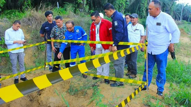 Personel Polda Riau melihat lobang yang dibuat sindikat pencurian minyak mentah untuk menjebol pipa bawah tanah milik PT Chevron.