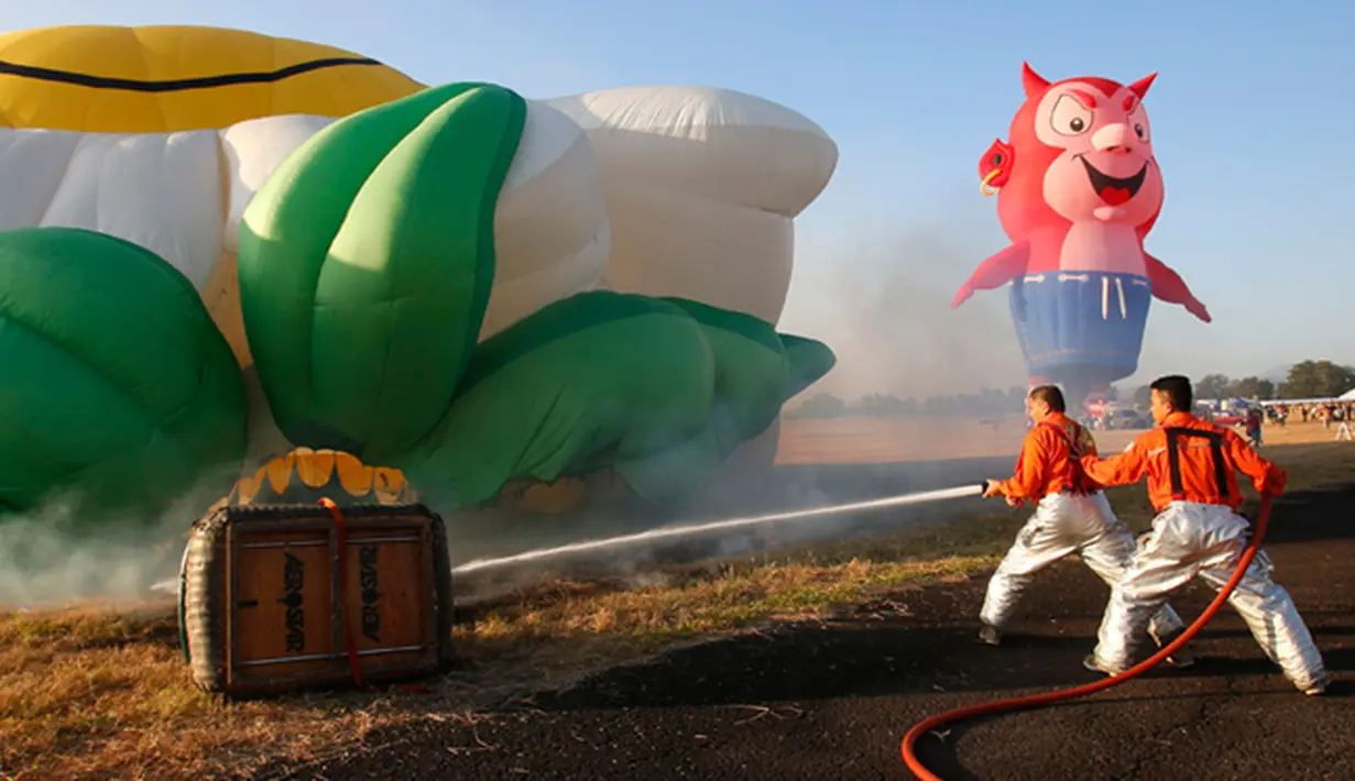 Pemadam kebakaran menyemprotkan air pada balon udara yang terbakar saat mengikuti Filipina International Hot Air Balloon Fiesta, Manila, Kamis (12/2/2015). (Reuters / Erik De Castro)