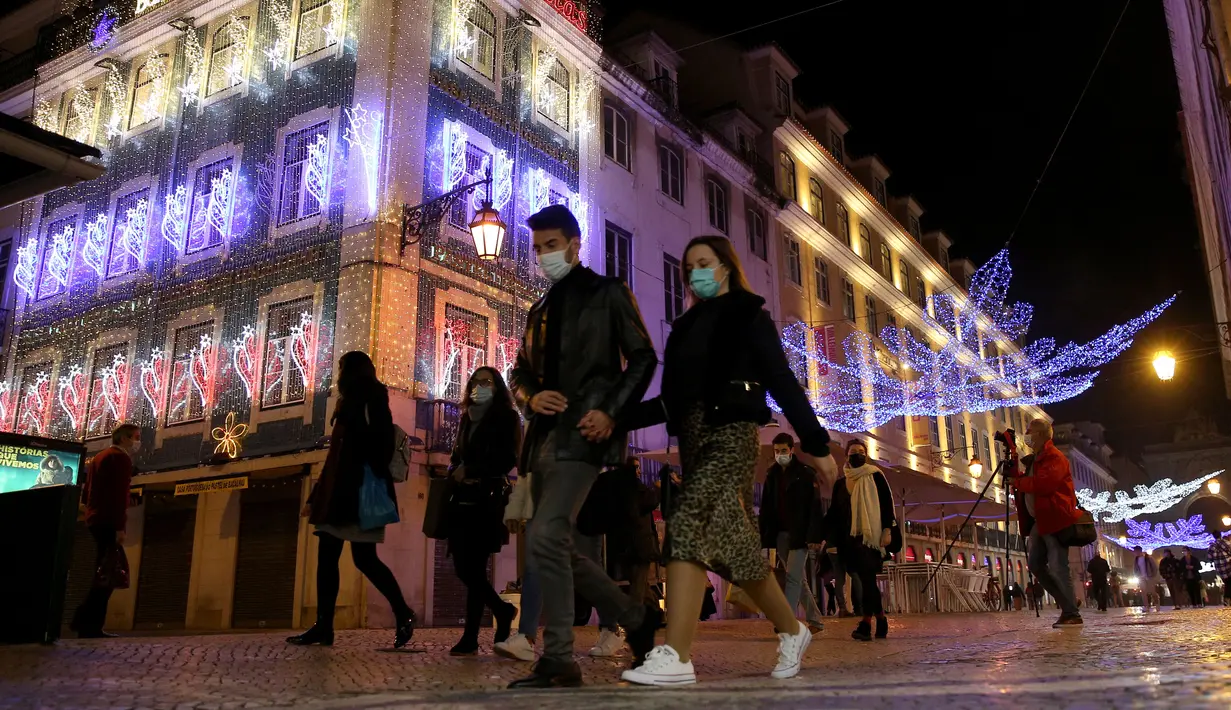 Sejumlah warga yang mengenakan masker berjalan di bawah lampu-lampu Natal dan Tahun Baru pada masa pandemi COVID-19 di Kota Lisbon, Portugal, 17 Desember 2020. Portugal akan memberlakukan aturan jam malam mulai pukul 23.00 pada Malam Tahun Baru. (Xinhua/Pedro Fiuza)