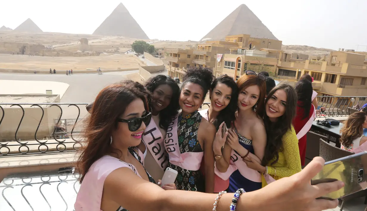 Para Kontestan Miss ECO Universe berselfie menggunakan tongsis dengan latar belakang segitiga piramida di pinggiran Kairo, Mesir (10/4). Pemenang Miss Eco Universe 2016 akan memenangkan hadiah uang tunai USD 10.000. (REUTERS/Mohamed Abd El Ghany)