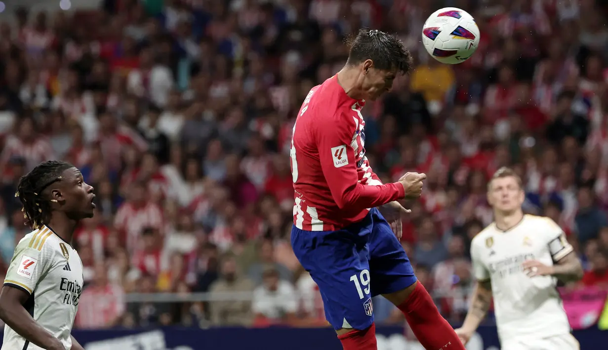 Pemain Atletico Madrid, Alvaro Morata (tengah), berhasil lepas dari penjagaan pemain Real Madrid, Eduardo Camavinga (kiri) dan menyundul bola ke gawang Real Madrid dalam pertandingan pekan keenam La Liga Spanyol 2023/2024 yang berlangsung di Metropolitano stadium, Madrid, Senin (25/9/2023).  (AFP/Oscar Del Pozo)