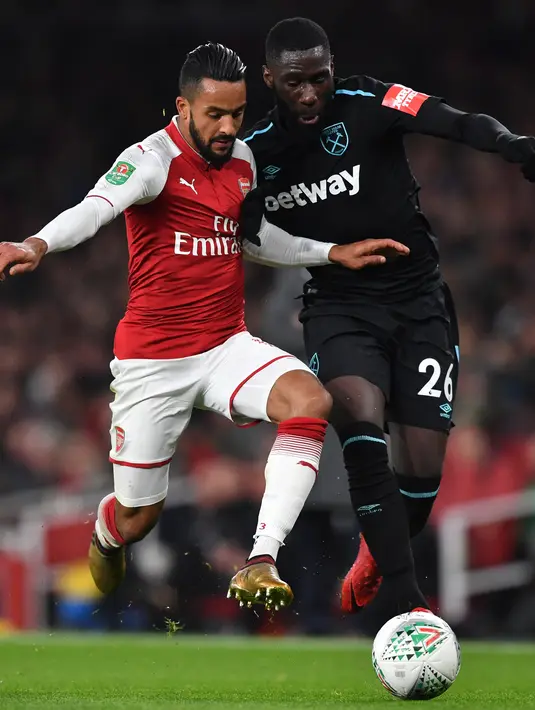 Pemain Arsenal, Theo Walcott berebut bola dengan pemain West Ham United, Arthur Masuaku pada laga perempat final Piala Liga Inggris di Emirates Stadium, Selasa (20/12). Arsenal berhasil melaju ke babak semifinal setelah menang 1-0. (AP /Alastair Grant)