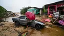 Seorang pria berjalan melewati sebuah mobil yang terdampar dan rumah-rumah yang rusak akibat banjir di Tumpat, negara bagian Kelantan, Malaysia, pada Rabu 4 Desember 2024. (MOHD RASFAN/AFP)