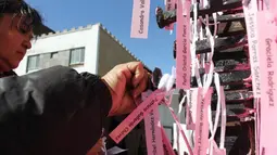 Ibu dan aktivis menempatkan nama-nama wanita yang dibunuh di Ciudad Juarez pada sebuah salib hitam di Jembatan Internasional Paso del Norte, Ciudad Juarez, Chihuahua, Meksiko, Rabu (7/3). (HERIKA MARTINEZ/AFP)