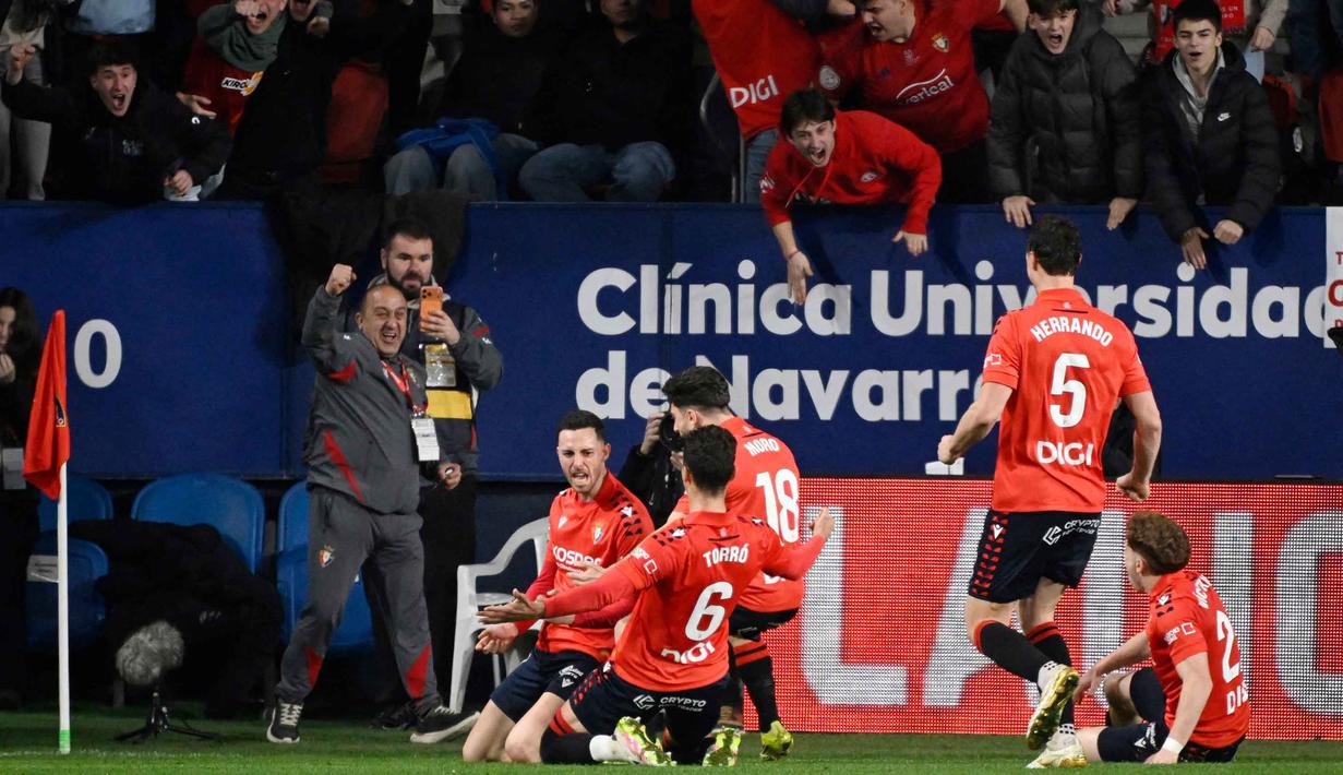 Jelang akhir pertandingan, pada menit ke-90, Stadion El Sadar kembali bergemuruh usai Raul Garcia berhasil mencetak gol yang memastikan Los Rojillos unggul 2-1 atas Real Madrid. Tampak dalam foto, penyerang Osasuna asal Spanyol, Raul Garcia (kiri), merayakan golnya selama pertandingan pekan ke-25 La Liga 2025/2026 melawan Real Madrid di Stadion El Sadar, Pamplona pada Sabtu 21 Februari 2026 waktu setempat atau Minggu (22/2/2026) dini hari WIB. (ANDER GILLENEA/AFP)