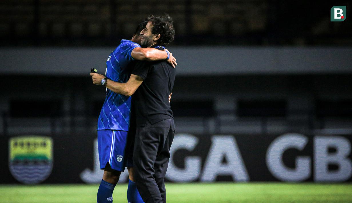 <p>Pelatih kepala Persib Bandung, Luis Milla (kiri) memeluk pemainnya, Ezra Walian setelah laga pekan ketiga BRI Liga 1 2023/2024 antara Persib Bandung melawan Dewa United di Stadion GBLA, Bandung, Jumat (14/07/2023). (Bola.com/Bagaskara Lazuardi)</p>