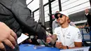 Pembalap Mercedes Lewis Hamilton bersalaman dengan penggemar dari Jepang saat jumpa pers jelang Grand Prix F1 di Sirkuit Suzuka, Jepang (5/10). (AP Photo/Toru Takahashi)