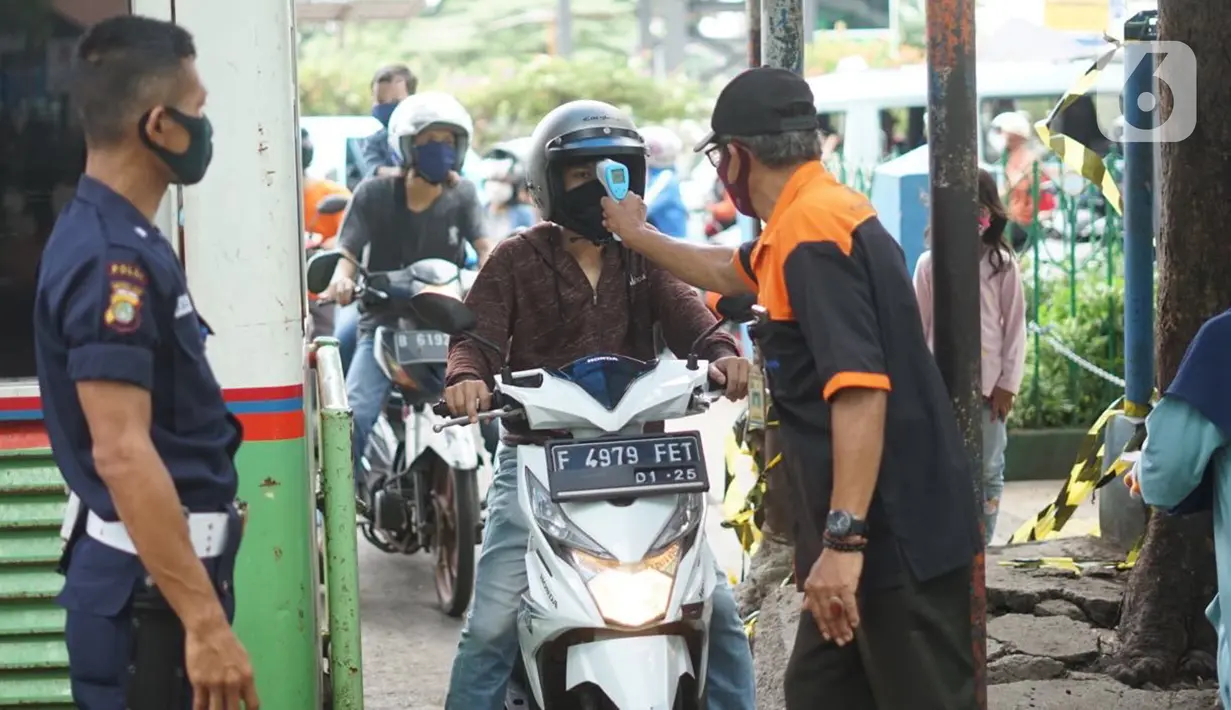 Petugas mengecek suhu tubuh pengunjung yang masuk ke kawasan Pasar Minggu, Jakarta, Selasa (23/6/2020). Pascapenutupan tiga hari terkait ditemukannya tiga pedagang yang positif COVID-19, pengunjung Pasar Minggu kini diwajibkan mencuci tangan dan cek suhu tubuh. (Liputan6.com/Immanuel Antonius)
