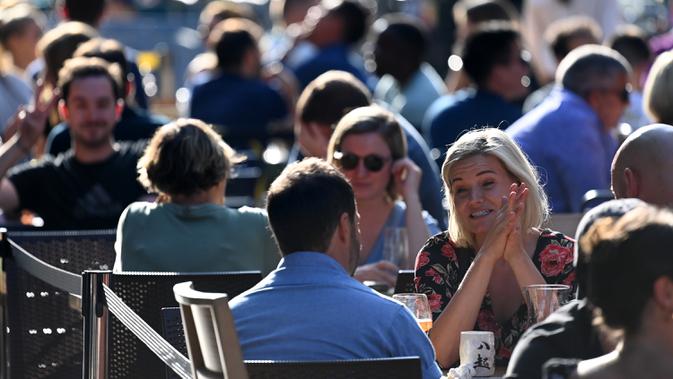 Orang-orang bersosialisasi di bawah sinar matahari di meja luar di Soho, London, ketika pemerintah Inggris mempertimbangkan pembatasan baru pada Minggu (20/9/2020). Inggris kemungkinan akan kembali memberlakukan tindakan lockdown akibat lonjakan tajam infeksi corona COVID-19 (DANIEL LEAL-OLIVAS/AFP)