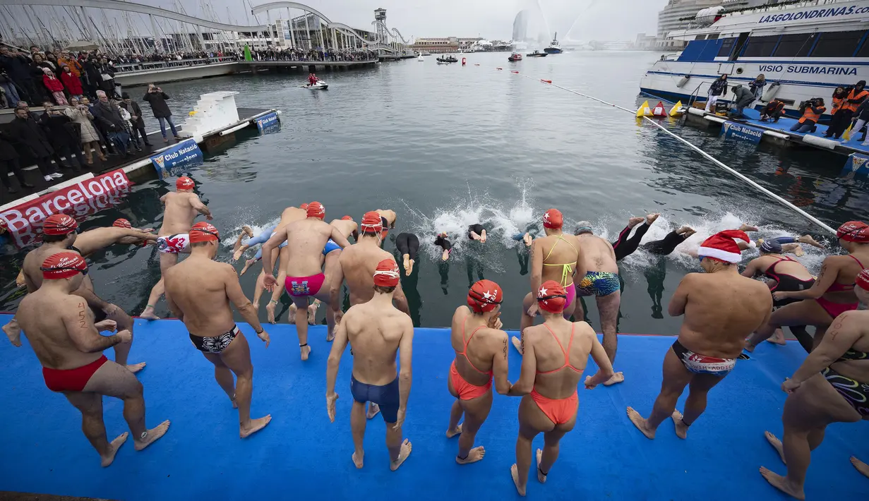 Sejumlah peserta melompat ke dalam air dalam ajang Copa Nadal yang berlangsung di Barcelona's Port Vell, Barcelona, Kamis (25/12/2025) waktu setempat. Acara tersebut diikuti lebih dari 450 peserta. (AFP/Josep Lago)