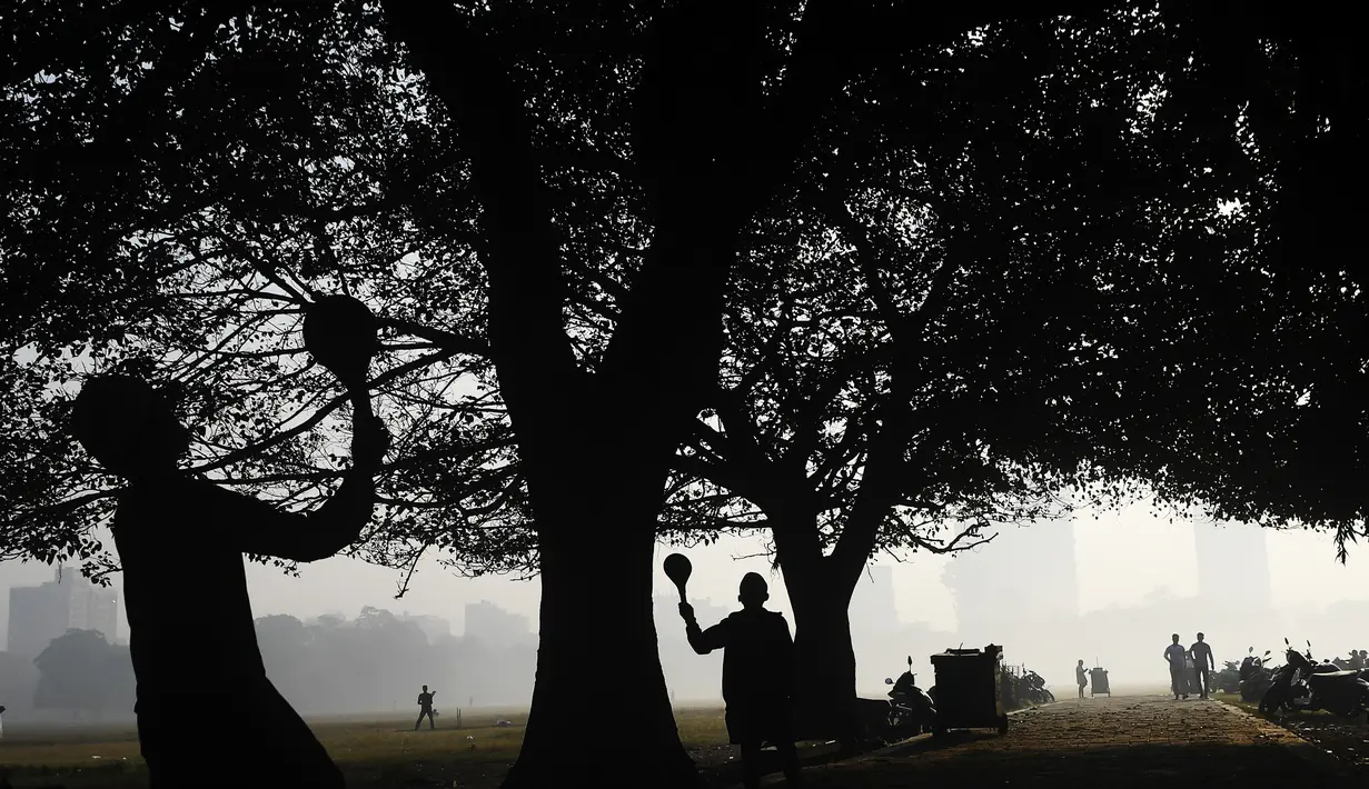 Siswa bermain di pagi yang berkabut di taman Maidan di Kolkata (29/11/2019). Taman Maidan  dipenuhi dengan patung-patung dan karya-karya seni bina, yang paling ketara ialah Peringatan Victoria. (AFP Photo/Dibyangshu Sarkar)
