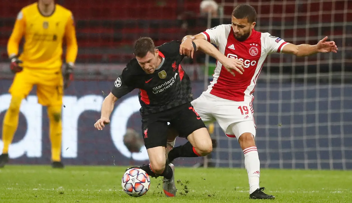 Gelandang Liverpool, James Milner berebut bola dengan pemain Ajax Amsterdam, Zakaria Labyad pada pertandingan pertama Grup D Liga Champions 2020 di Johan Cruijff Arena, Kamis (22/10/2020) dini hari WIB. Liverpool susah payah menang tipis 1-0 di kandang Ajax. (AP Photo/Peter Dejong)