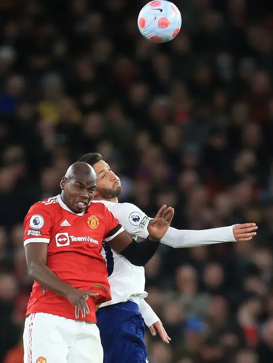 Gelandang Manchester United (MU) Paul Pogba (kiri) berebut bola dengan gelandang Tottenham Hotspur Rodrigo Bentancur pada pekan ke-29 Liga Inggris di Old Trafford, Minggu (13/3/2022) dini hari WIB. Ronaldo mencetak hattrick untuk membawa MU menang 3-2. (Lindsey Parnaby/AFP)