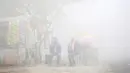 Warga duduk di samping toko saat kabut tebal akibat polusi menyelimuti  Delhi, India (1/12). Kabut ini diklaim sebagai kabut asap terparah yang dialami oleh New Delhi dalam 17 tahun yang telah mengurangi jarak pandang. (REUTERS/Cathal McNaughton)