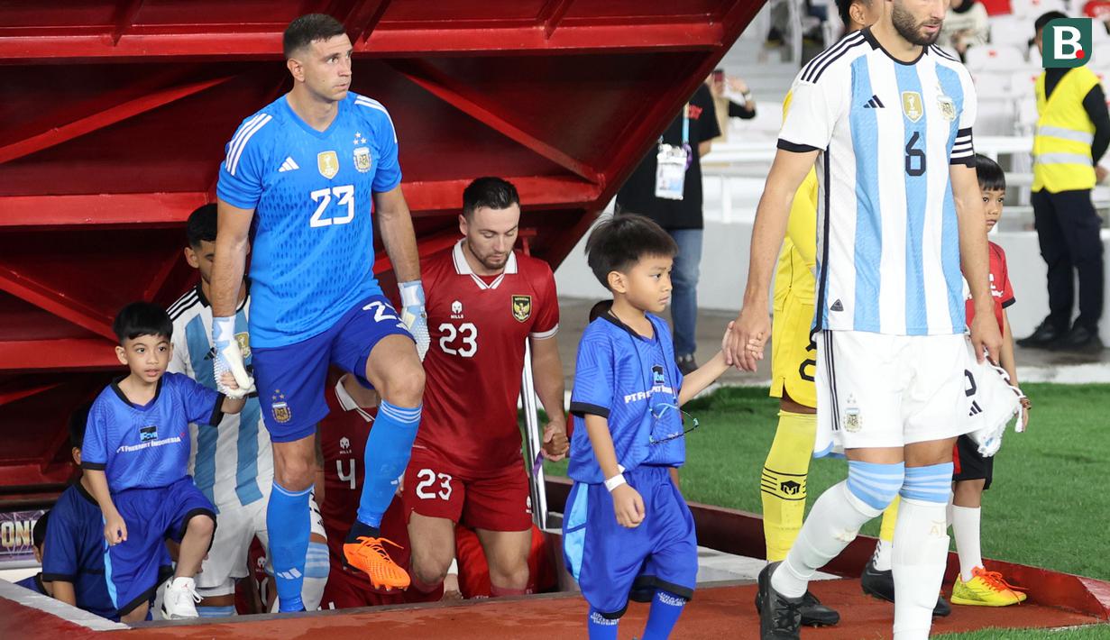 Cucu Presiden RI Joko Widodo, Jan Ethes (kiri) saat menjadi player escort kiper Timnas Argentina, Emiliano Martinez pada laga FIFA Matchday melawan Timnas Indonesia di Stadion Utama Gelora Bung Karno (SUGBK), Senayan, Jakarta, Senin (19/06/2023). (Bola.com/Bagaskara Lazuardi)