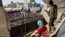 Kegiatan ini digelar di tengah bayang-bayang blokade dan kondisi kemanusiaan yang masih berlangsung di Gaza. Tampak dalam foto, seorang anak laki-laki dan perempuan mengamati dari sebuah bangunan yang rusak parah saat orang-orang berkumpul selama perayaan pernikahan massal untuk para pengantin Palestina yang diselenggarakan oleh Yayasan Bantuan Kemanusiaan Turki (IHH) di Kota Gaza pada 11 Mei 2026. (Omar AL-QATTAA/AFP)