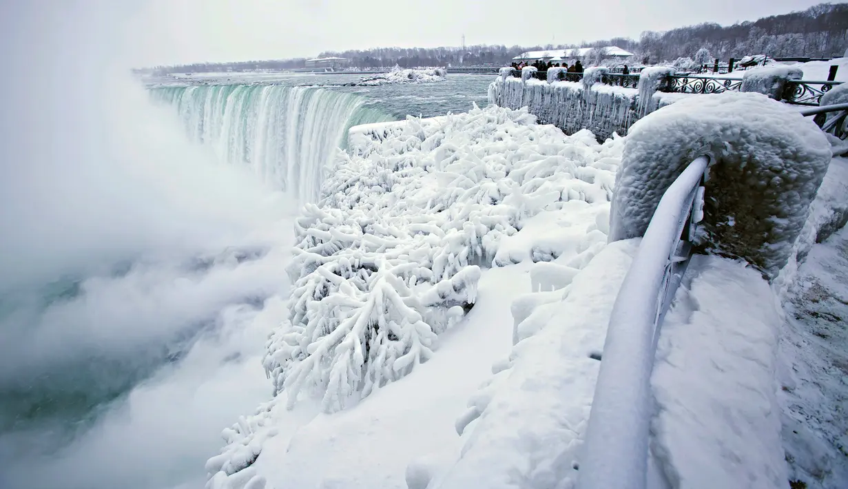 Pengunjung mengabadikan pemandangan Horseshoe Falls di Air Terjun Niagara yang membeku di Ontario, Kanada, Jumat (29/12). Cuaca dingin melanda sebagian besar wilayah utara Amerika Serikat di akhir tahun ini. (Aaron Lynett/Canadian Press via AP)