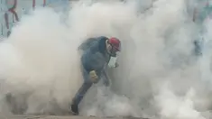 Asap gas air mata menyelimuti seorang demonstran saat aksi  menentang Presiden Venezuela Nicolas Maduro, di Caracas, kamis (20/4). Tiga orang dikabarkan tewas dalam aksi demonstrasi tersebut.  (AFP PHOTO / Juan BARRETO)
