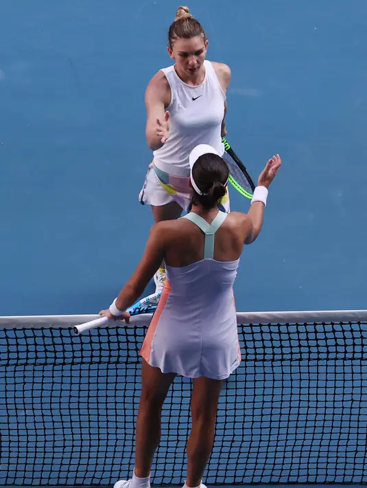 Petenis Rumania, Simona Halep (atas) menghampiri Garbine Muguruza asal Spanyol usai pertandingan semifinal tunggal putri Australia Terbuka di Melbourne, Australia, Kamis (30/1/2020). Halep gagal ke final Australia Terbuka 2020 usai kalah dari Muguruza 7-6, 7-5. (DAVID GREY/AFP)