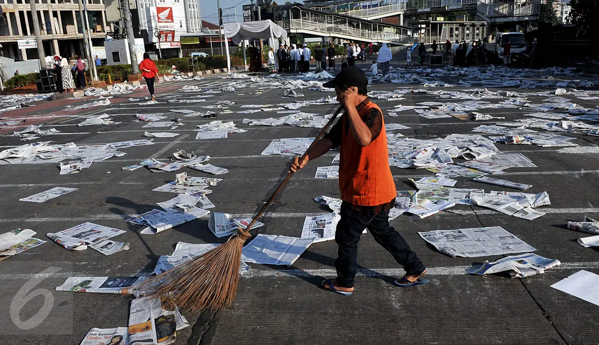 Petugas membersihkan sampah koran di ruas Jalan Jatinegara Barat, Jakarta, Jumat (17/7/2015). Sampah koran bekas tersebut sebelumnya digunakan warga untuk alas salat Idul Fitri 1436 H. (Liputan6.com/Johan Tallo)