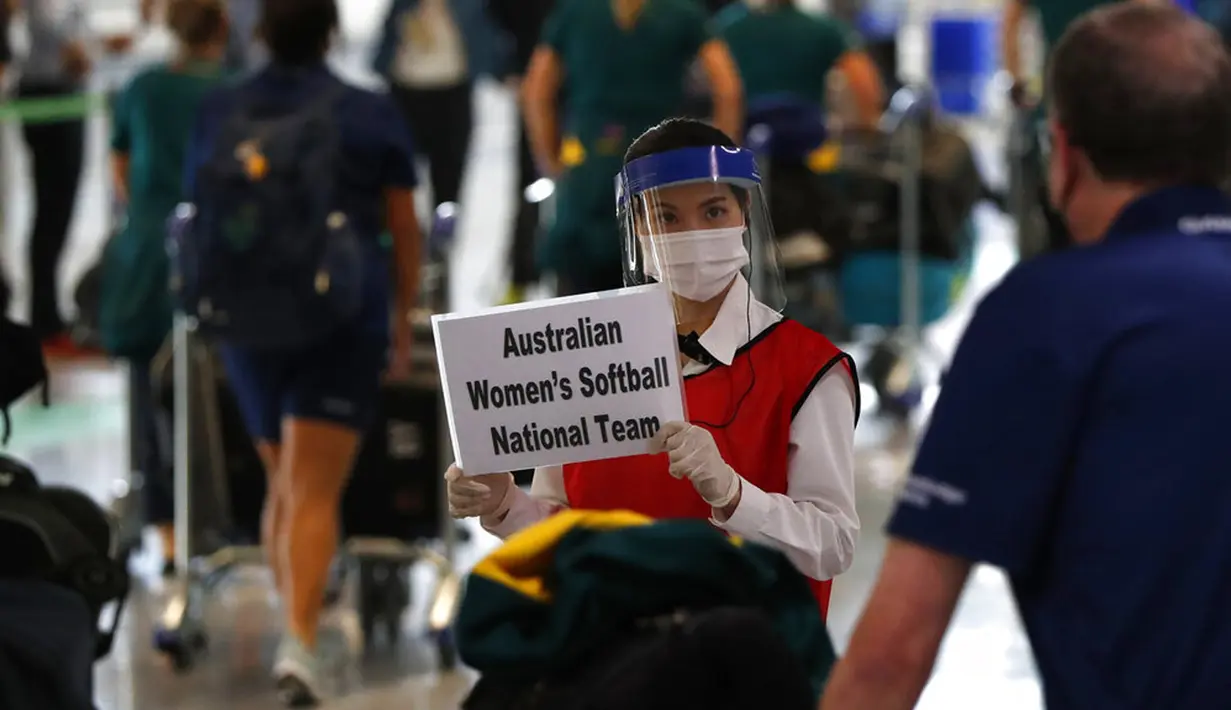 Seorang wanita mengenakan masker dan pelindung wajah menyambut kedatangan pemain timnas softball Australia di Bandara internasional Narita, Jepang, Selasa (1/6/2021). Timnas softball Australia termasuk di antara yang paling awal datang untuk Olimpiade Tokyo. (Issei Kato/Pool Photo via AP)