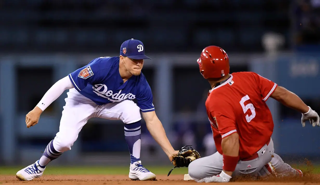Pemain Los Angeles Dodgers, Enrique Hernandez (kiri) menangkap bola saat pemain Los Angeles Angels, Albert Pujols berusaha mendapatkan poin selama  inning pertama dari pertandingan bisbol pramusim di Los Angeles (26/3). (AP Photo/Mark J. Terrill)