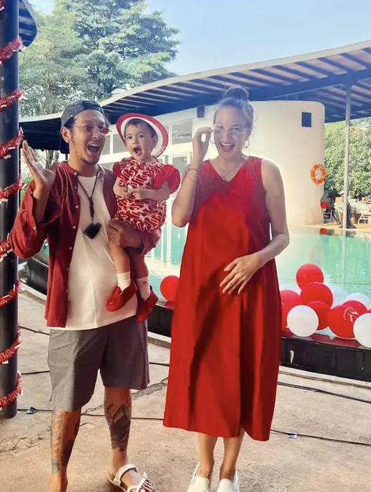Nadine Chandrawinata tampil dengan dress merah sepatu putih, serasi dengan Dimas Anggara dan si kecil. [Instagram/@nadinelist]