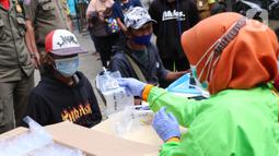 Petugas memberikan kantong kepada warga untuk menjalani tes GeNose C19 usai terjaring razia penggunaan masker di Kelurahan Sudimara Barat, Kota Tangerang, Kamis (27/5/2021). Tes tersebut untuk menekan penyebaran corona COVID-19 di wilayah tersebut. (Liputan6.com/Angga Yuniar)