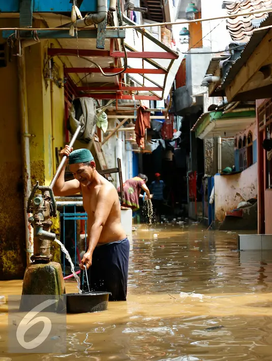 Warga mengambil air bersih saat banjir melanda pemukiman Kampung Pulo, Jakarta, Rabu (25/11/2015). Air aliran kali Ciliwung mulai memasuki rumah warga sekitar pukul 03.00 Wib dini hari tadi. (Liputan6.com/Yoppy Renato)
