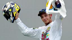 Pebalap MotoGP asal Italia, Valentino Rossi mengangkat helm merayakan gelar juara di Sirkuit Sepang, Malaysia, Minggu (12/10/2003). (AFP/Jimin Lai)