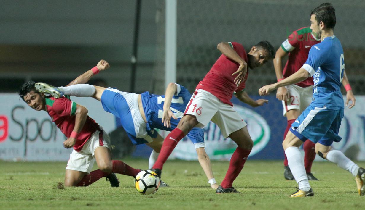Pemain timnas Indonesia U-23, Putu Gede (kiri) saat berebut bola dengan pemain Uzbekistan pada laga PSSI Anniversary Cup 2018 di Stadion Pakansari, Bogor, (03/5/2018). Indonesia U-23 bermain imbang 0-0. (Bola.com/Nick Hanoatubun)