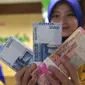 Petugas Bank memperlihatkan uang pecahan Rp100.000 dan Rp 50.000, Jakarta, Selasa (29/12). Di pasar spot, Senin (28/12), rupiah melemah tipis 0,08% ke Rp 13.642 per dollar AS. (Liputan6.com/Angga Yuniar)