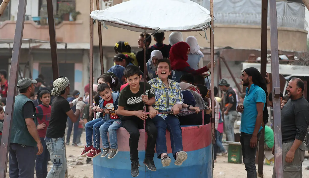 Anak-anak Suriah bermain di taman darurat selama perayaan Idul Fitri, hari libur Muslim yang dimulai pada akhir bulan puasa Ramadan, di Binnish di provinsi Idlib, Suriah barat laut yang dikuasai pemberontak, (26/5/2020). (AFP Photo/Omar Haj Kadour)